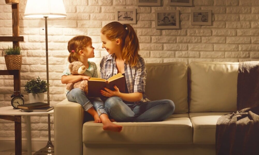 Frau und Mädchen sitzen im Licht einer Stehlampe auf Sofa